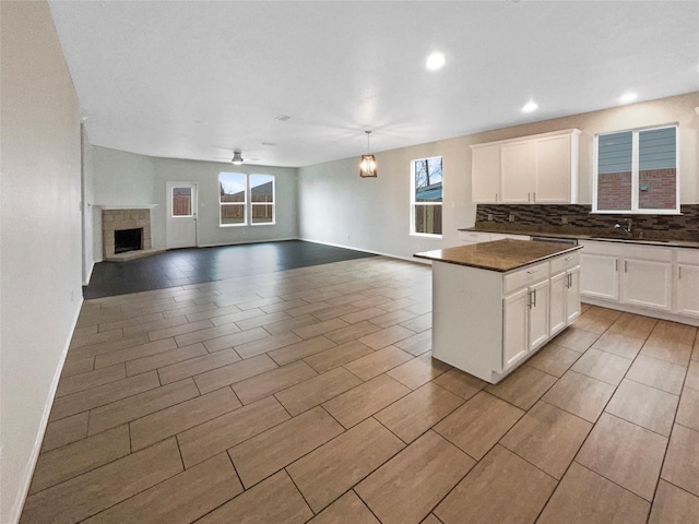 kitchen featuring a kitchen island, pendant lighting, white cabinetry, decorative backsplash, and ceiling fan