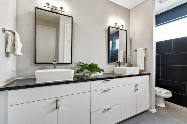 bathroom featuring vanity, tile walls, tile patterned floors, and toilet