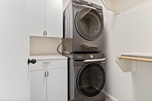 washroom with cabinets and stacked washer / drying machine