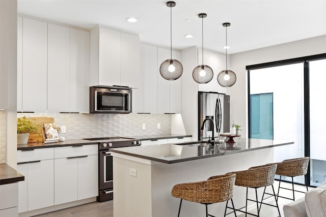 kitchen with hanging light fixtures, appliances with stainless steel finishes, sink, and white cabinets