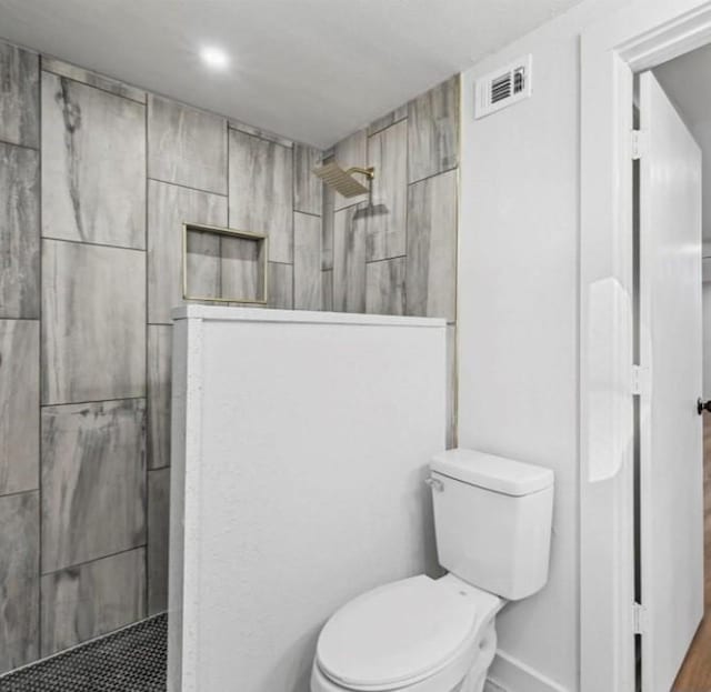 bathroom with toilet and a tile shower