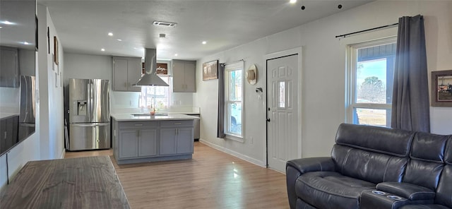 kitchen featuring gray cabinets, island range hood, sink, stainless steel refrigerator with ice dispenser, and light wood-type flooring