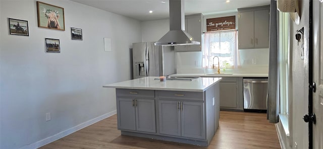 kitchen with extractor fan, a kitchen island, appliances with stainless steel finishes, sink, and gray cabinetry