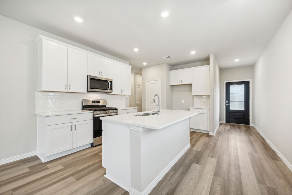 kitchen featuring a kitchen island with sink, sink, white cabinetry, and appliances with stainless steel finishes