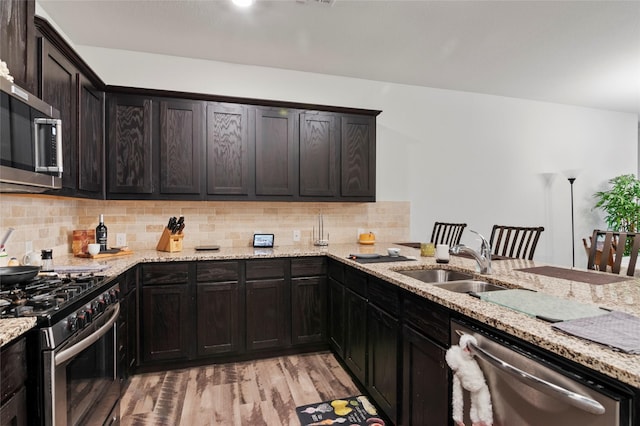 kitchen featuring stainless steel appliances, light stone countertops, and sink