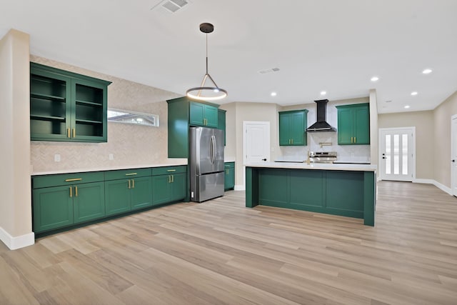 kitchen with wall chimney exhaust hood, light wood-type flooring, pendant lighting, stainless steel appliances, and decorative backsplash