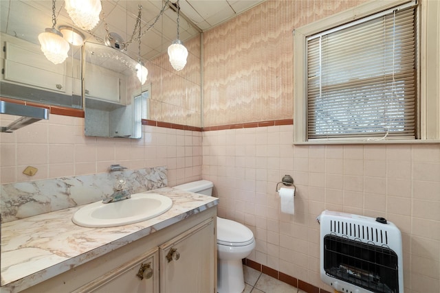 bathroom with tile patterned floors, toilet, heating unit, tile walls, and vanity