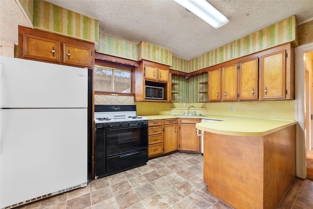 kitchen with range with gas stovetop, black microwave, white fridge, kitchen peninsula, and a textured ceiling