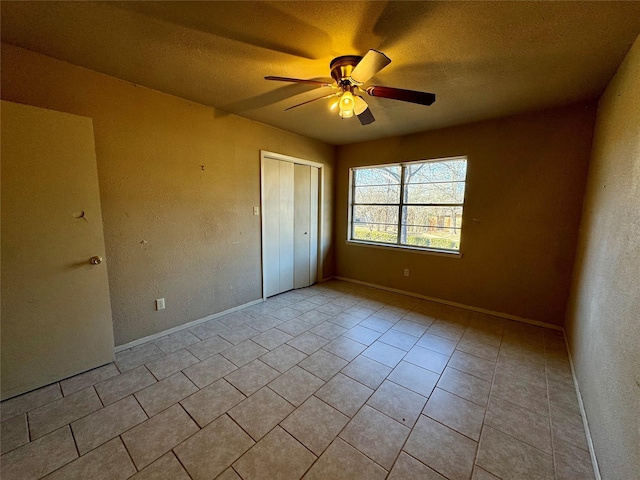 unfurnished bedroom with ceiling fan, a closet, a textured ceiling, and light tile patterned floors