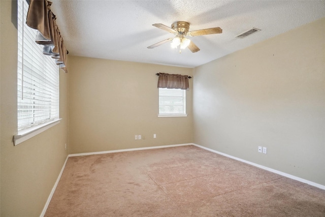 unfurnished room with light carpet, ceiling fan, and a textured ceiling