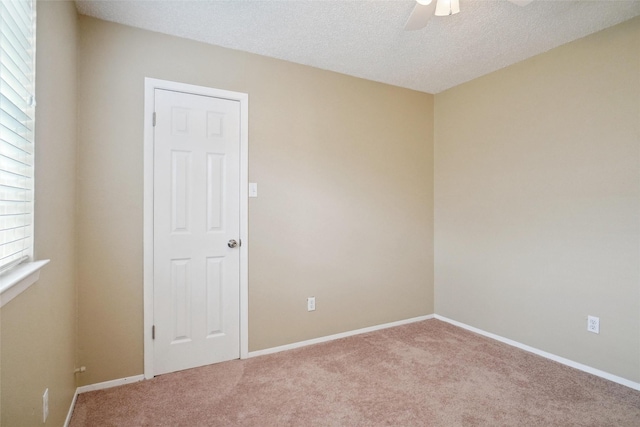 spare room featuring ceiling fan, light carpet, and a textured ceiling