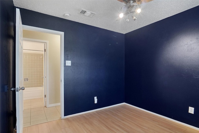 empty room with light hardwood / wood-style flooring and a textured ceiling