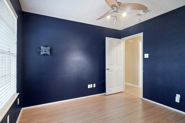 unfurnished room featuring a healthy amount of sunlight, ceiling fan, and light wood-type flooring