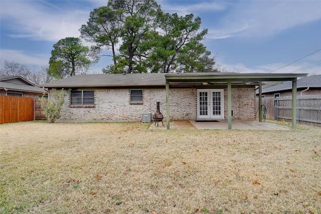 back of property featuring a patio, a yard, french doors, and central AC unit