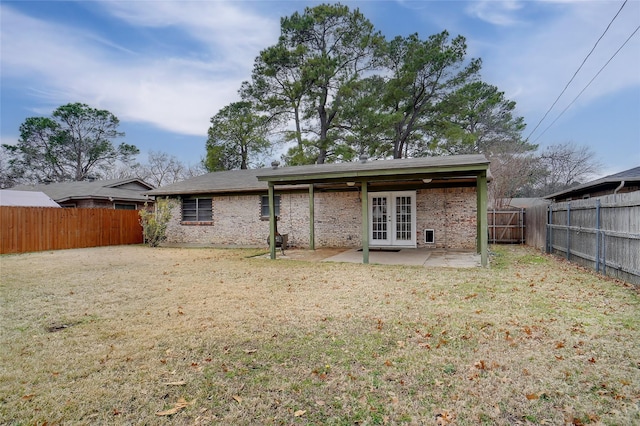 rear view of property featuring french doors, a patio area, and a lawn