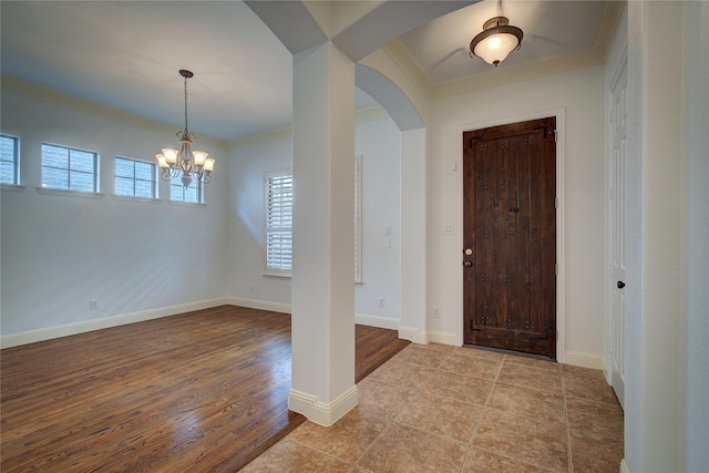 foyer with an inviting chandelier, ornamental molding, and light hardwood / wood-style floors