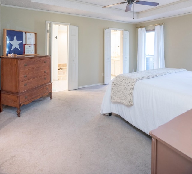 bedroom with crown molding, light colored carpet, ensuite bathroom, and a raised ceiling