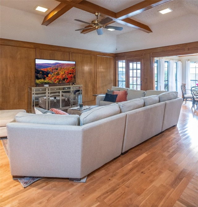 living area with wood walls, coffered ceiling, wood finished floors, a ceiling fan, and beam ceiling