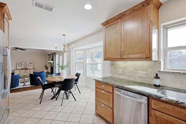 kitchen featuring tasteful backsplash, decorative light fixtures, a wealth of natural light, and stainless steel dishwasher