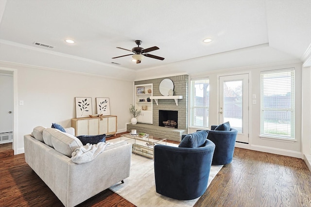 living room featuring a brick fireplace, hardwood / wood-style flooring, ornamental molding, and ceiling fan