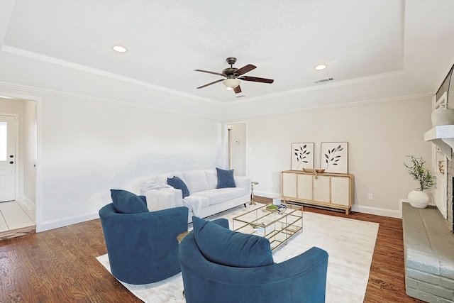 living room featuring ceiling fan, dark hardwood / wood-style floors, a fireplace, and a tray ceiling