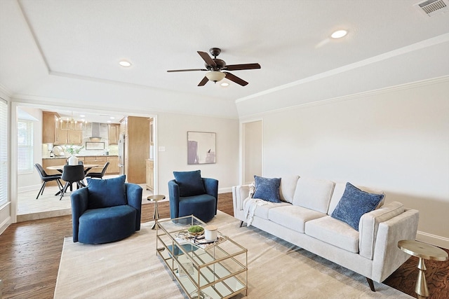 living room with crown molding, a tray ceiling, wood-type flooring, and ceiling fan