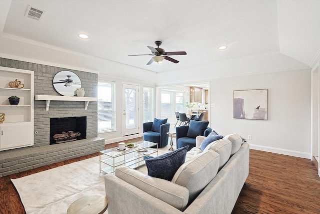 living room featuring dark hardwood / wood-style flooring, a brick fireplace, built in shelves, and ceiling fan