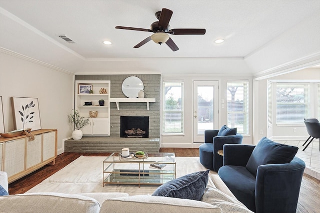 living room featuring a fireplace, a tray ceiling, wood-type flooring, and ceiling fan