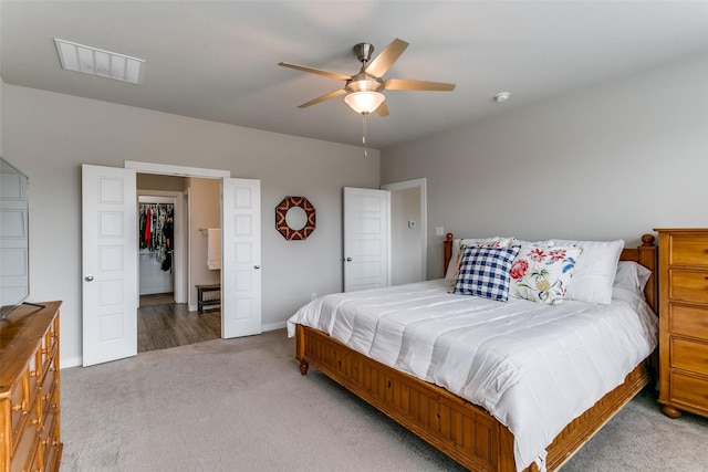 carpeted bedroom with ceiling fan and a spacious closet