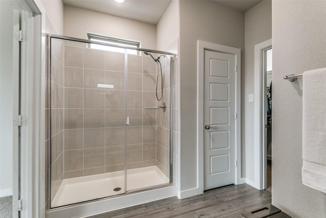 bathroom featuring wood-type flooring and a shower with door