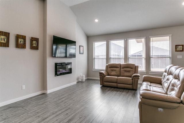 living room featuring lofted ceiling, a wealth of natural light, and light hardwood / wood-style flooring