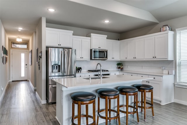 kitchen with sink, an island with sink, white cabinets, and appliances with stainless steel finishes