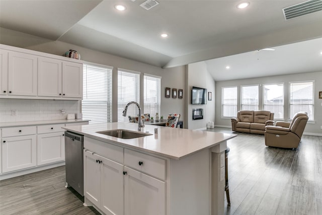 kitchen featuring sink, white cabinetry, vaulted ceiling, a center island with sink, and stainless steel dishwasher