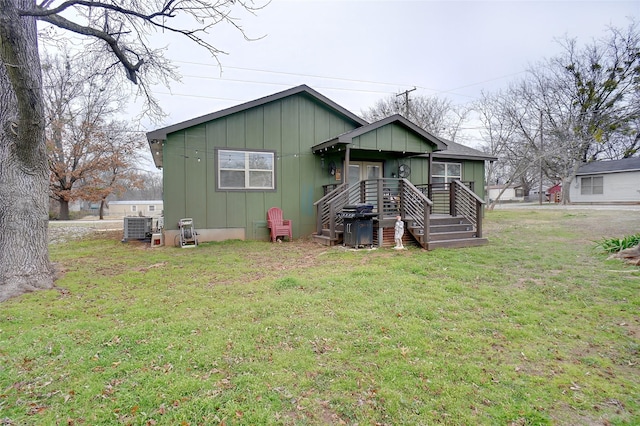 view of front of property with board and batten siding, central AC, and a front yard