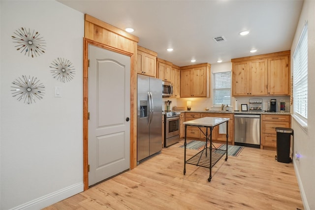 kitchen featuring stainless steel appliances, baseboards, a sink, and light wood-style flooring