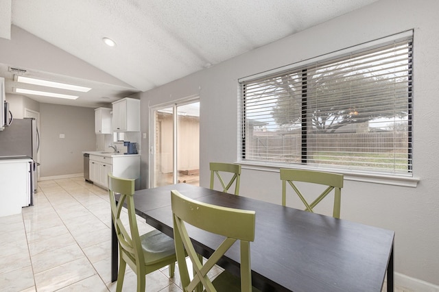 dining area featuring sink, a textured ceiling, vaulted ceiling, and a healthy amount of sunlight