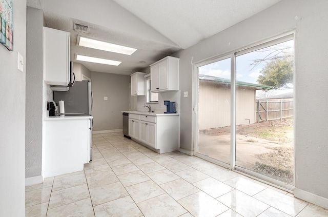 kitchen with sink, vaulted ceiling, stainless steel appliances, and white cabinets