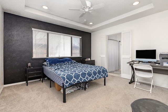 bedroom featuring ceiling fan, a tray ceiling, and carpet floors