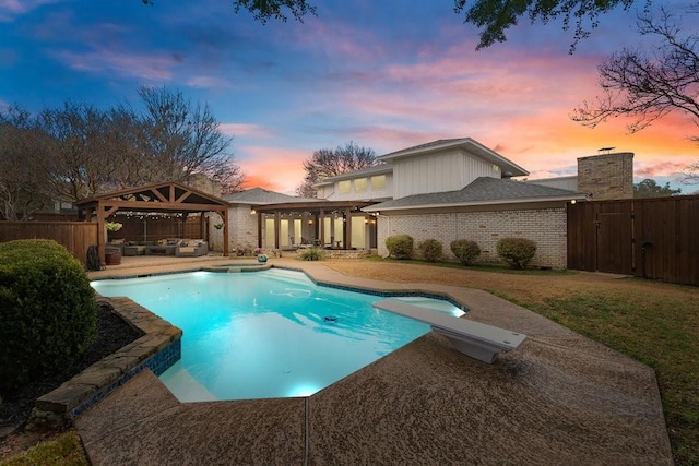 pool at dusk featuring a gazebo, a diving board, an outdoor hangout area, and a patio