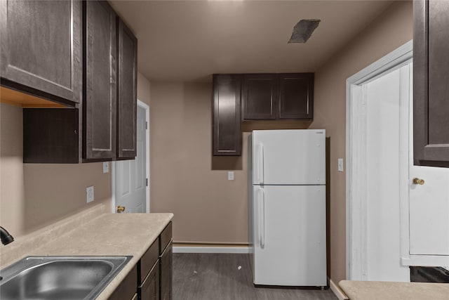 kitchen featuring sink, dark brown cabinets, white refrigerator, and hardwood / wood-style floors