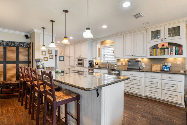 kitchen with a kitchen island, pendant lighting, a breakfast bar area, and dark stone countertops