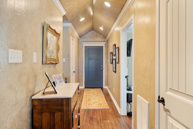 entryway with ornamental molding, vaulted ceiling, and light wood-type flooring