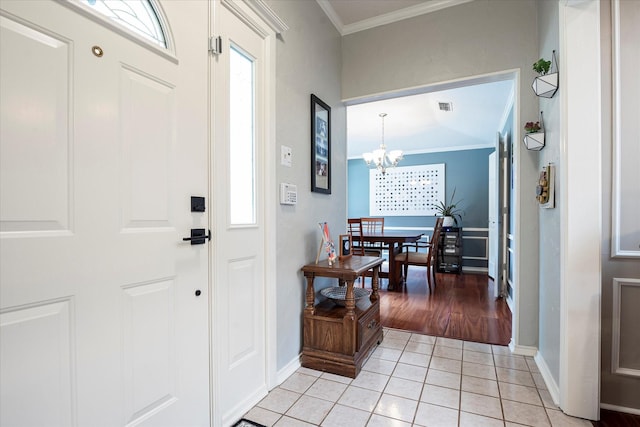 tiled foyer entrance featuring plenty of natural light, ornamental molding, and a notable chandelier