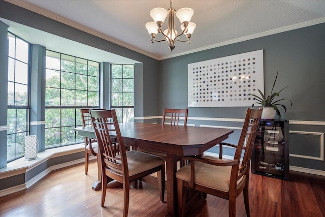 dining area with hardwood / wood-style flooring, ornamental molding, and a notable chandelier