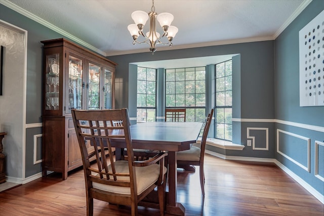 dining space featuring a notable chandelier, crown molding, plenty of natural light, and light wood-type flooring