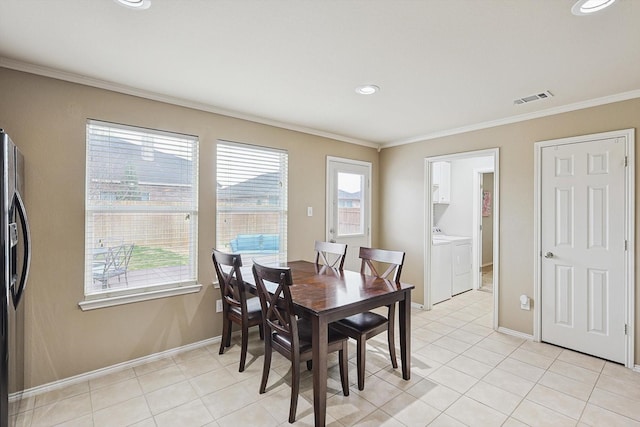 dining room featuring crown molding, light tile patterned flooring, and washer and clothes dryer