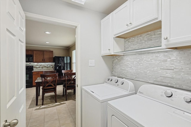 clothes washing area featuring cabinets, crown molding, light tile patterned floors, and washer and clothes dryer