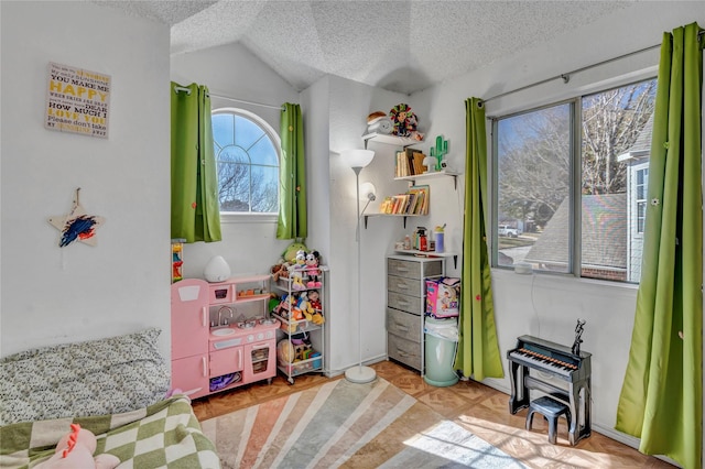 playroom with light parquet floors, vaulted ceiling, and a textured ceiling