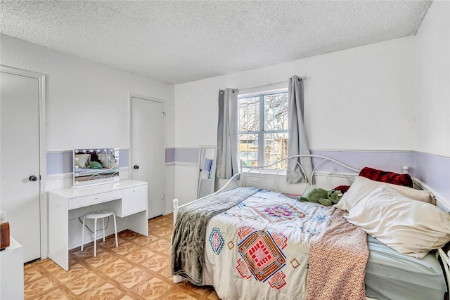 bedroom with a textured ceiling and light parquet floors