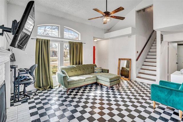 living room featuring ceiling fan, a fireplace, high vaulted ceiling, and a textured ceiling